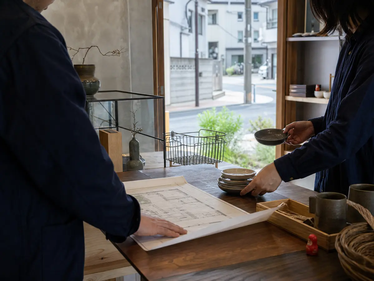 Two people preparing a neighborhood shop in Japan around a floor plan